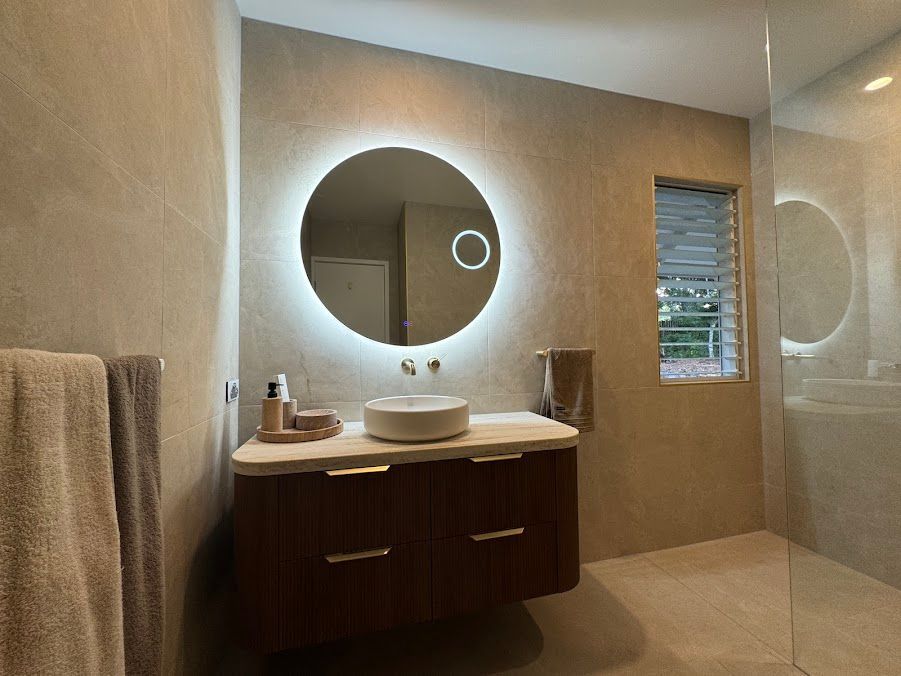 A Bathroom With a Sink and a Round Mirror — Coastwide Plumbing Solutions in Maroochydore, QLD