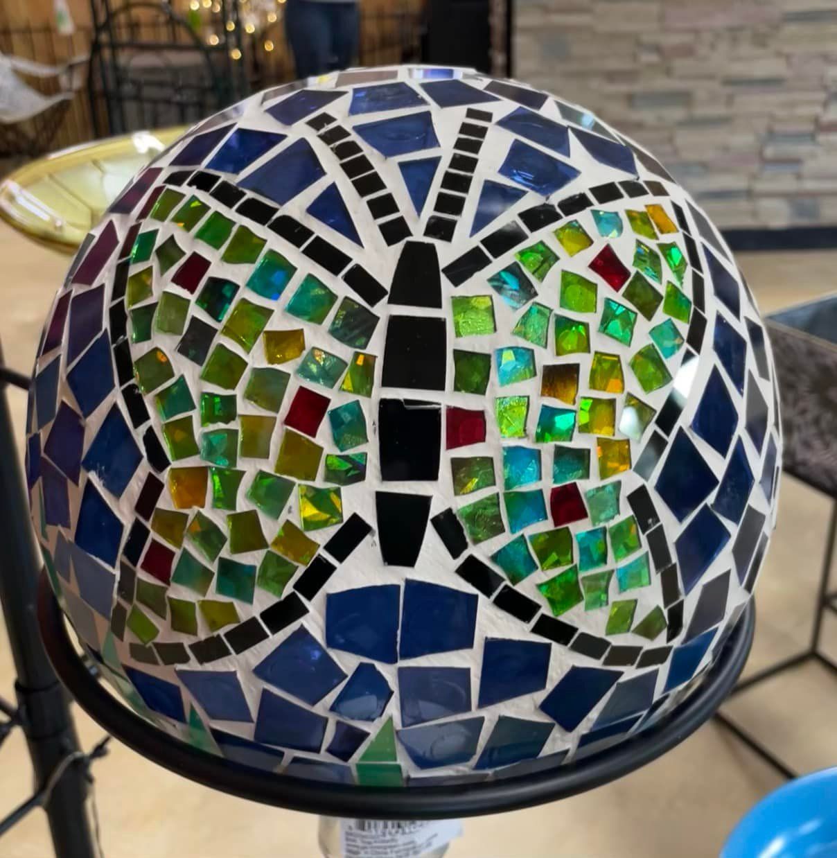 Mosaic butterfly sphere, blues, greens, and reds, atop black metal stand.