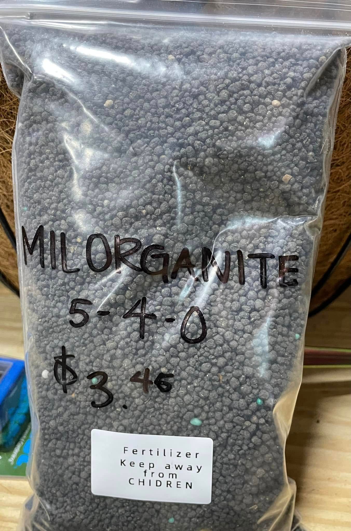 Bag of Milorganite fertilizer, labeled 5-4-0, priced $3.46. Dark pellets fill the bag.