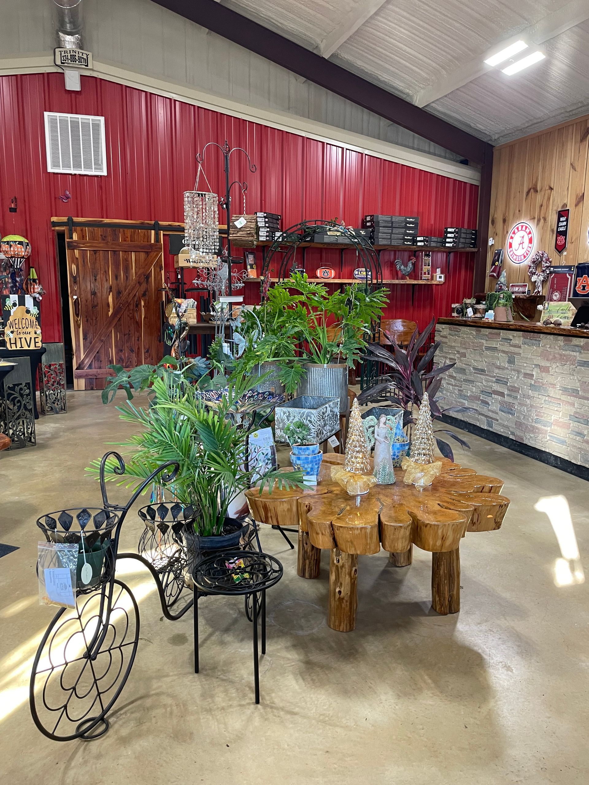 Interior of a store, red wall, various decorative items, plants, and a wooden table.