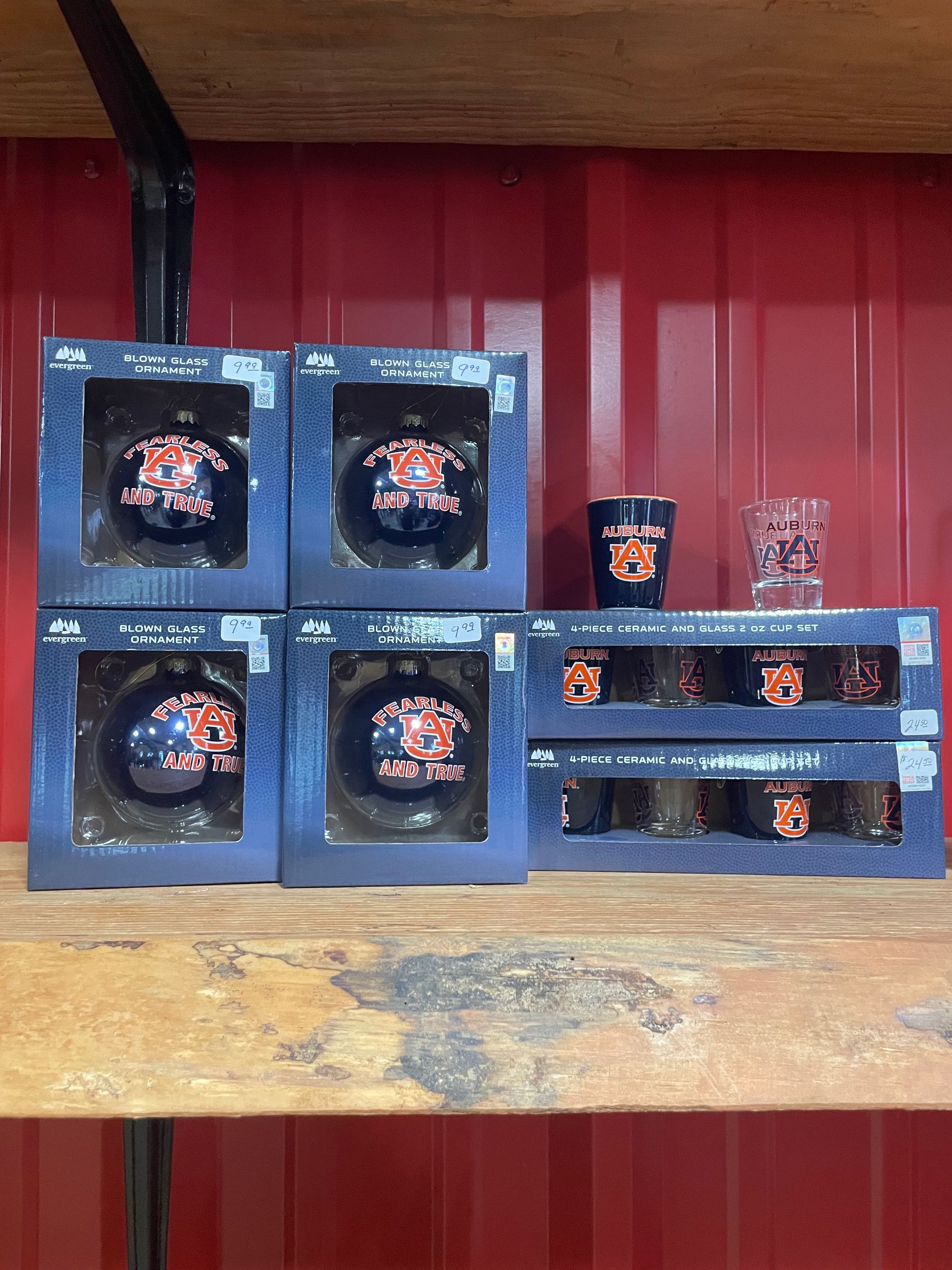 Shelves with boxed glassware, including ornaments and shot glasses, against a red wall.