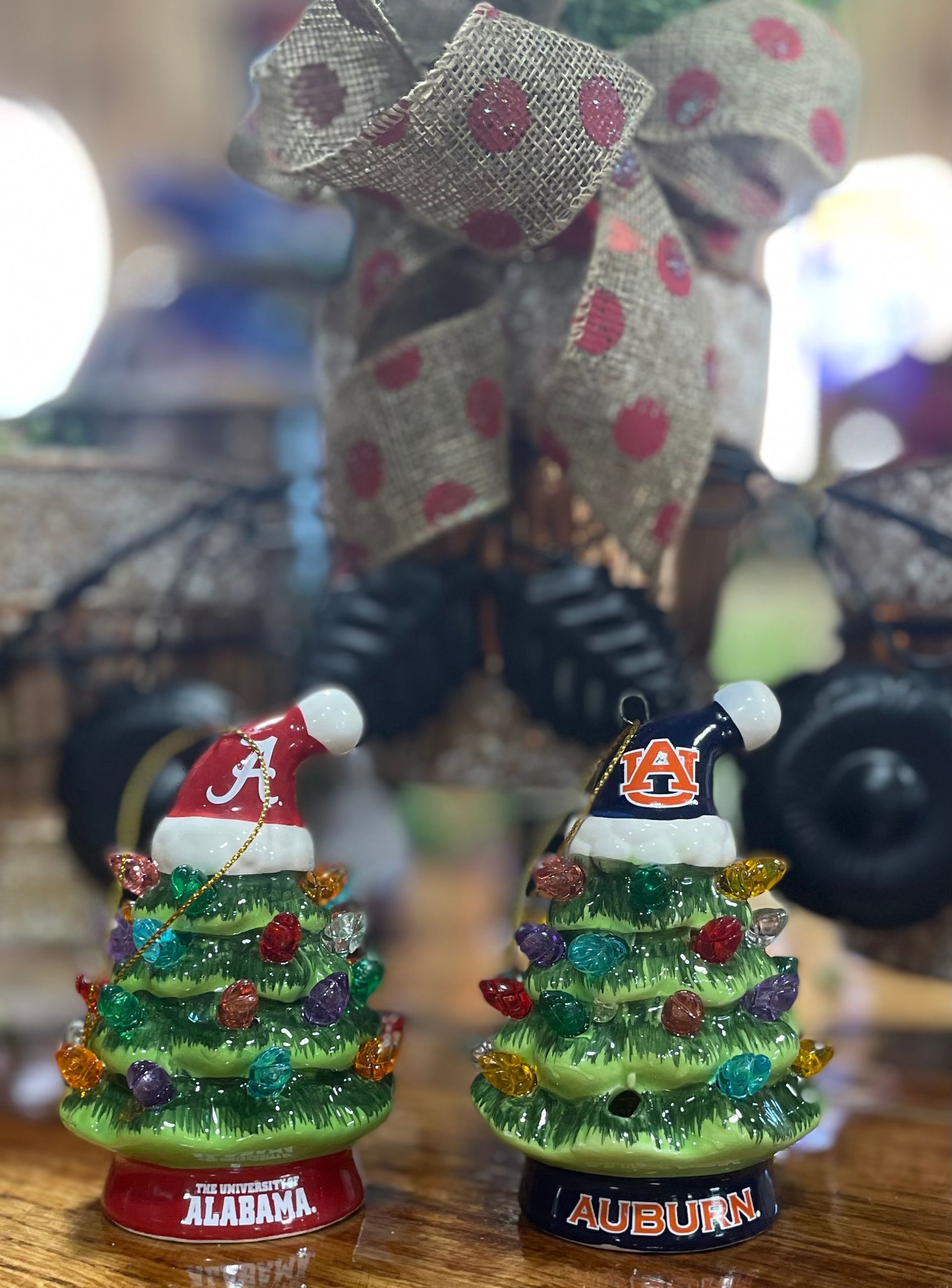 Two Christmas tree ornaments; one Alabama, one Auburn, with Santa hats.