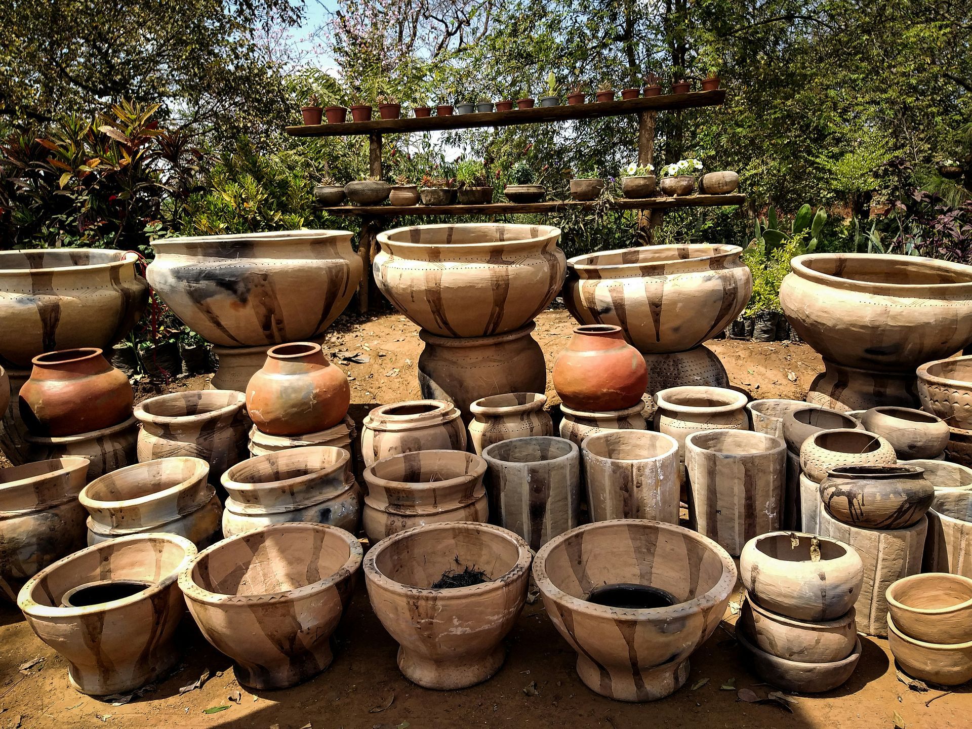 Assortment of earthenware pots of varying sizes, shapes, and textures outdoors.