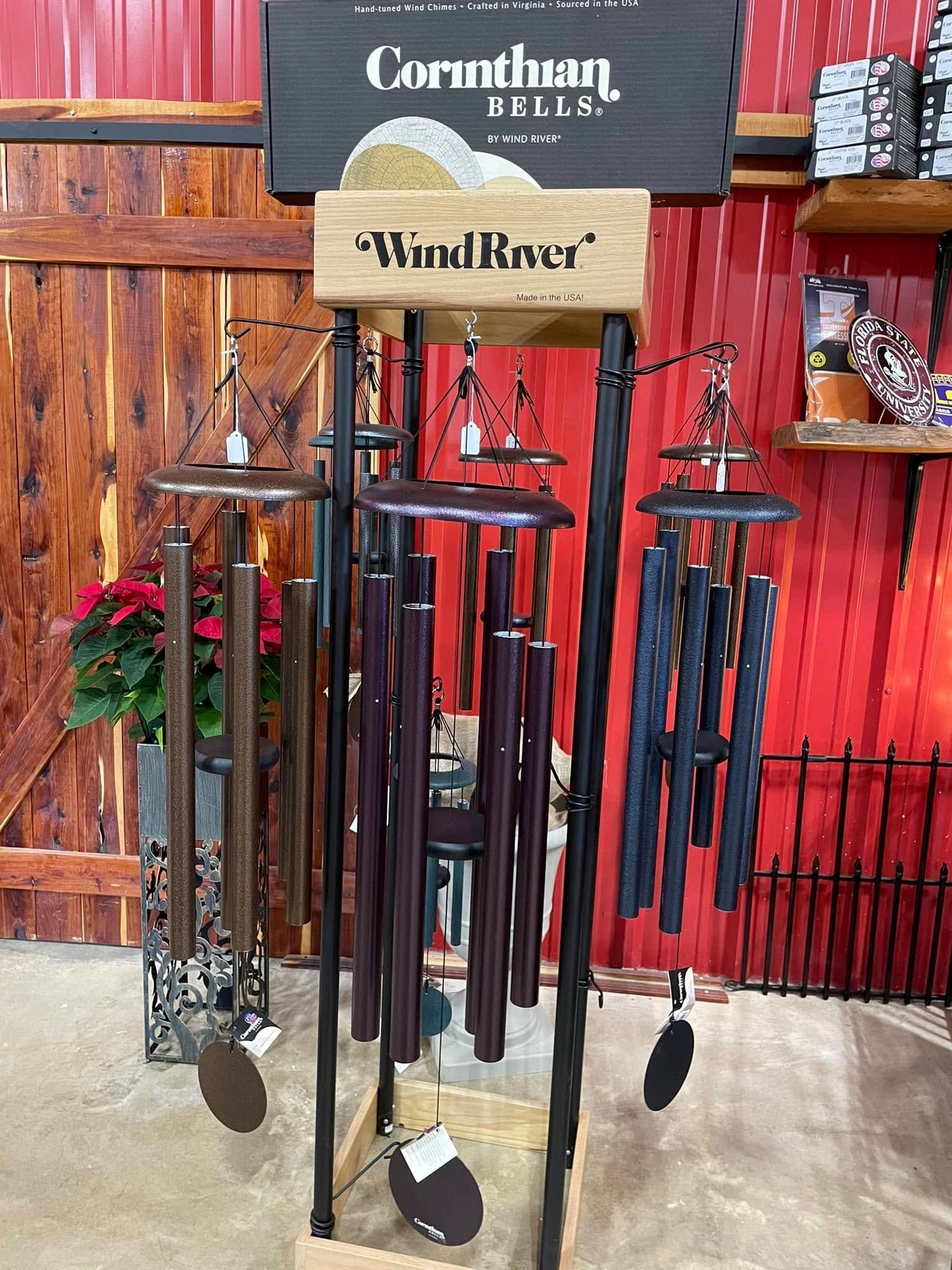 Display of Wind River and Corinthian Bells wind chimes in a store with red wall and wood door.