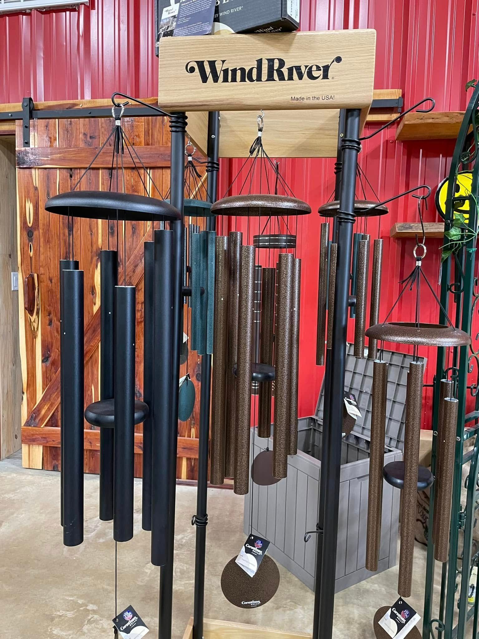 Wind chimes display with black and bronze tubes, in a store with red walls.