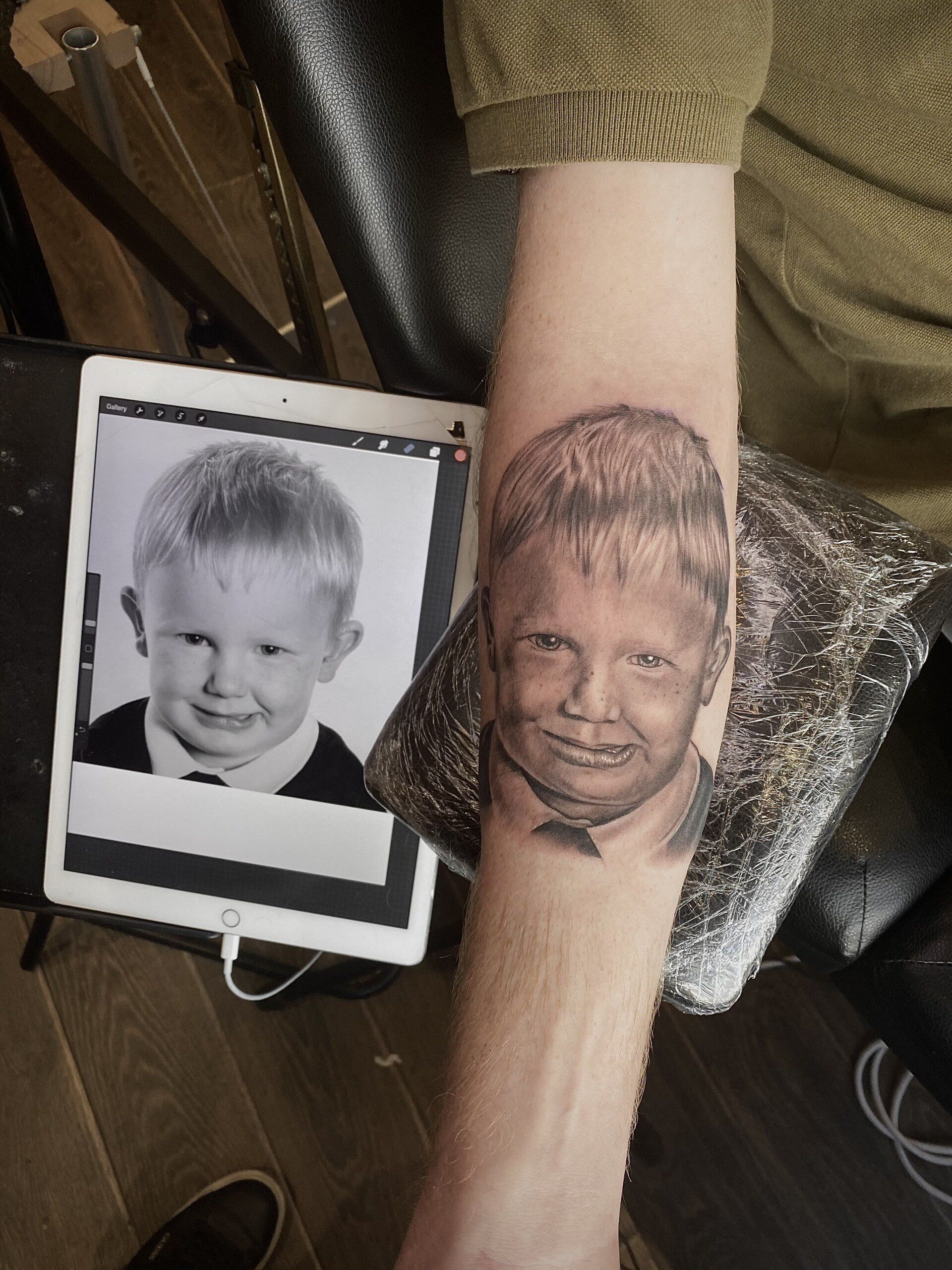 A man has a tattoo of a child 's face on his arm