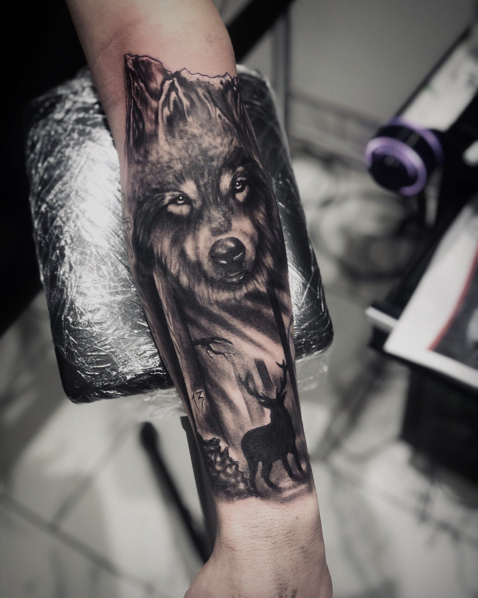 A person has a tattoo of a wolf on their forearm.