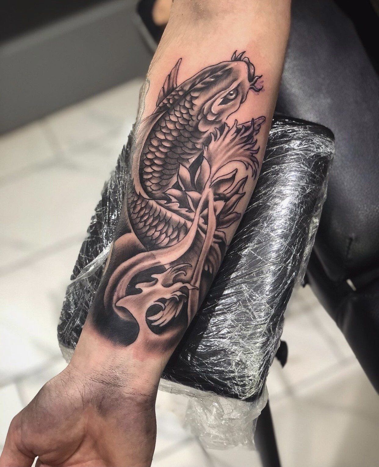A man has a tattoo of a fish on his forearm