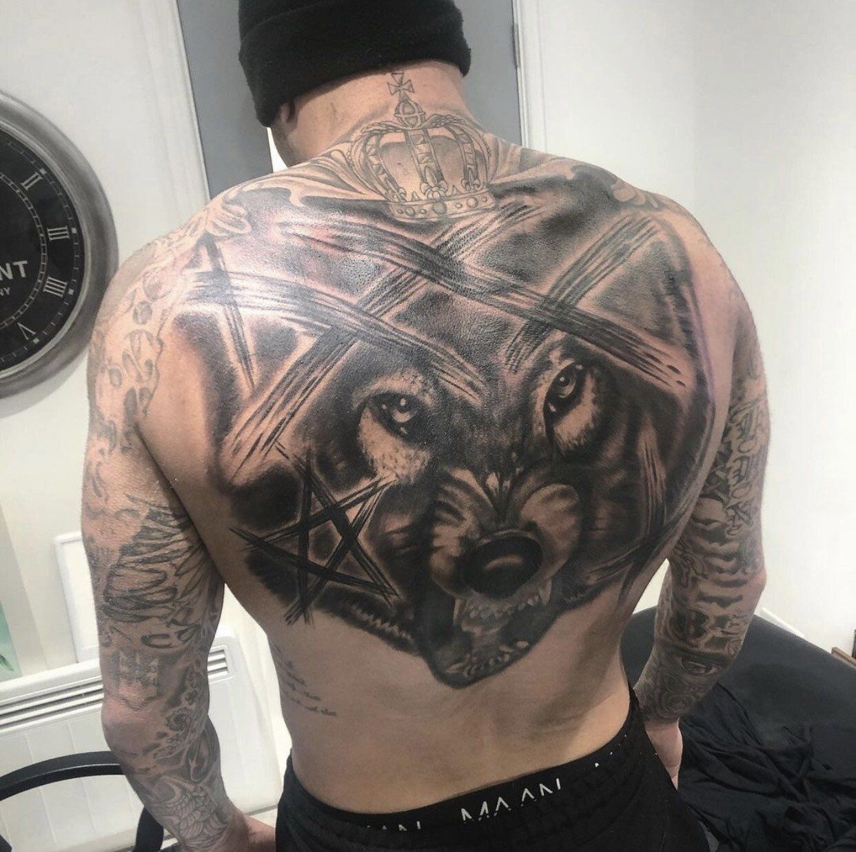 A man has a large wolf tattoo on his back