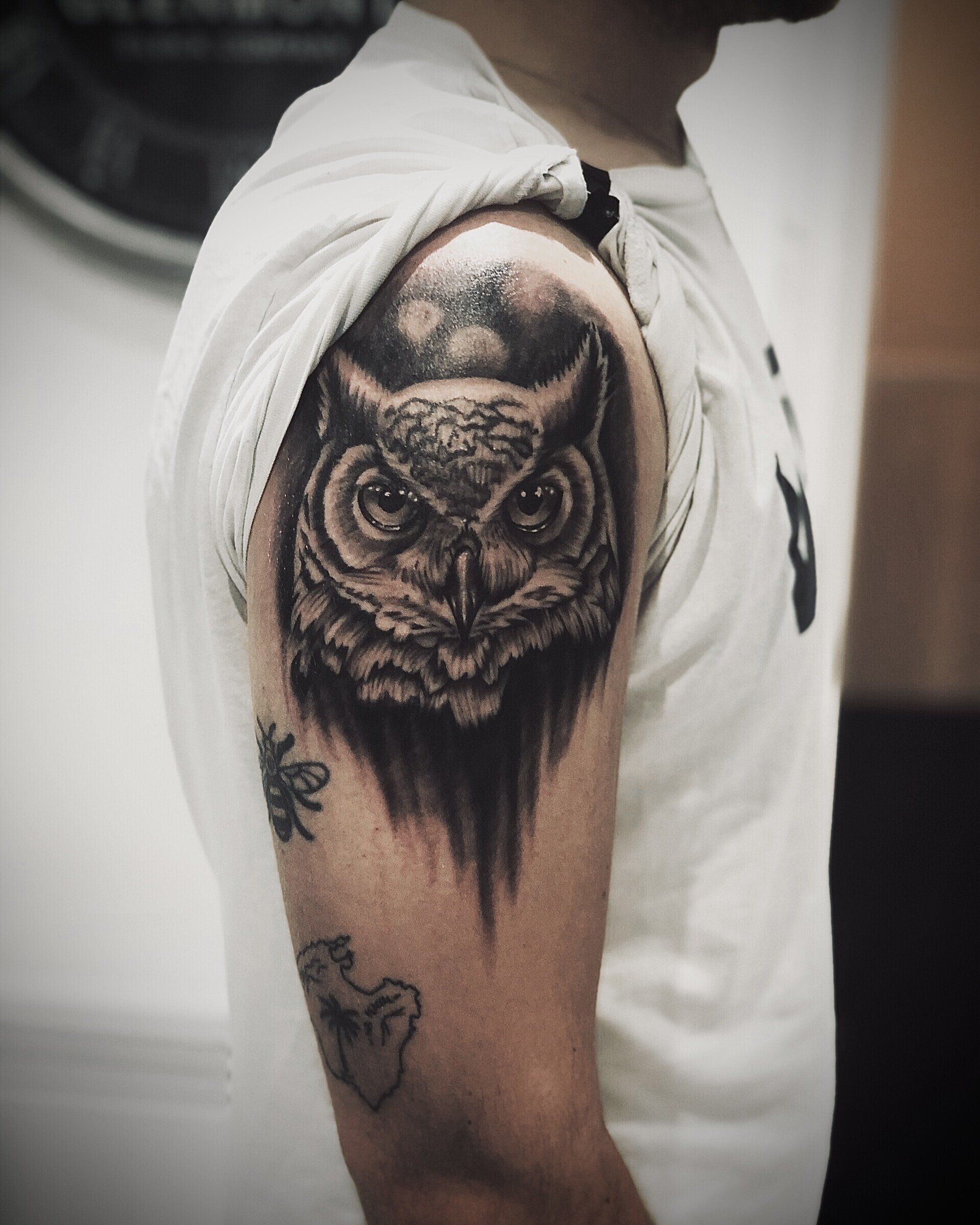 A man has a tattoo of an owl on his arm