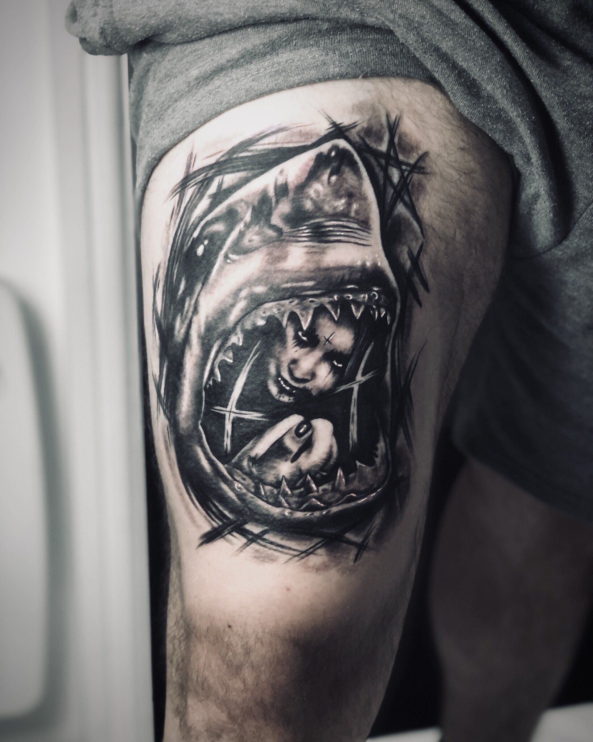 A black and white tattoo of a shark on a person 's leg