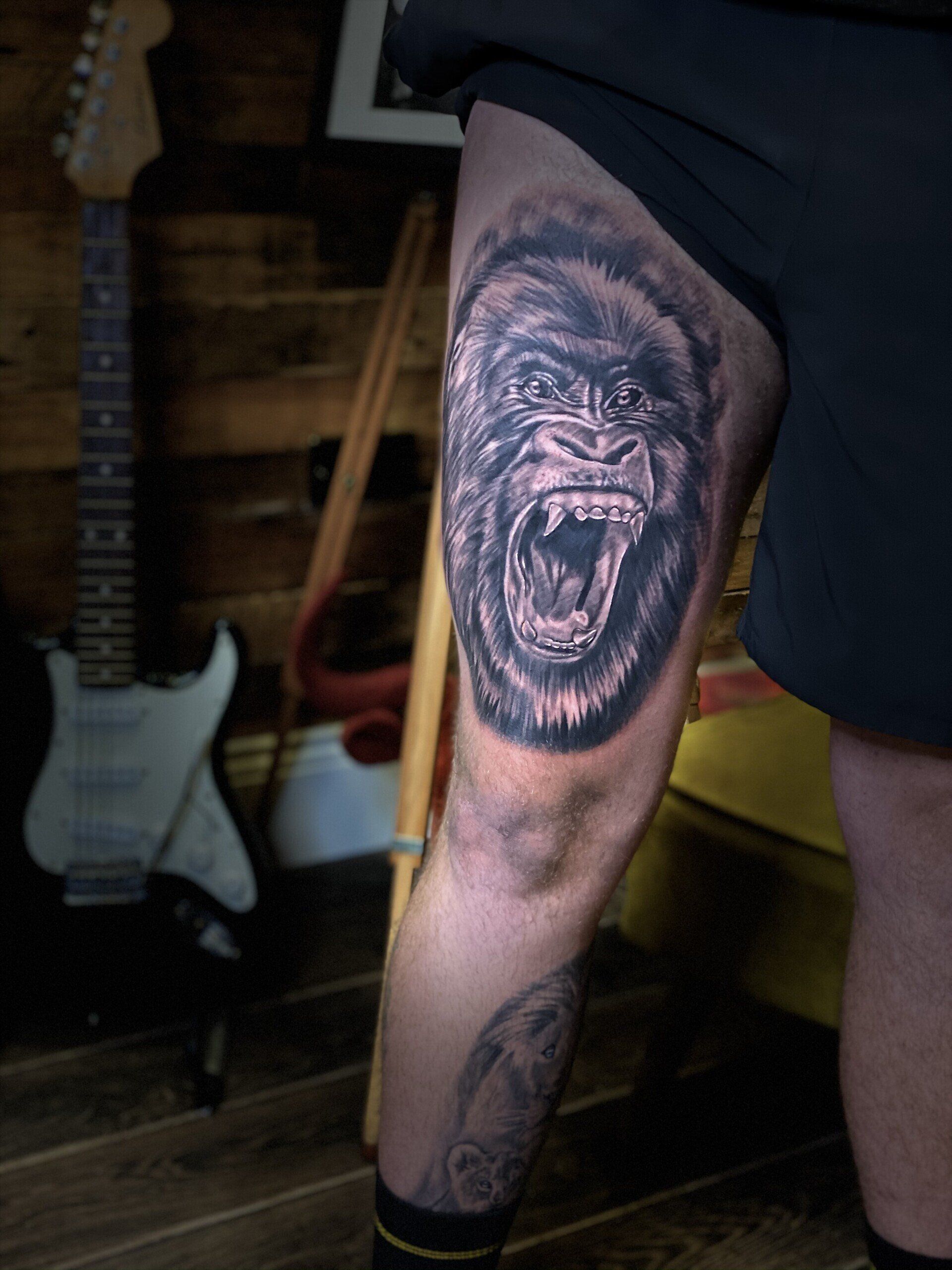 A man has a tattoo of a gorilla on his leg