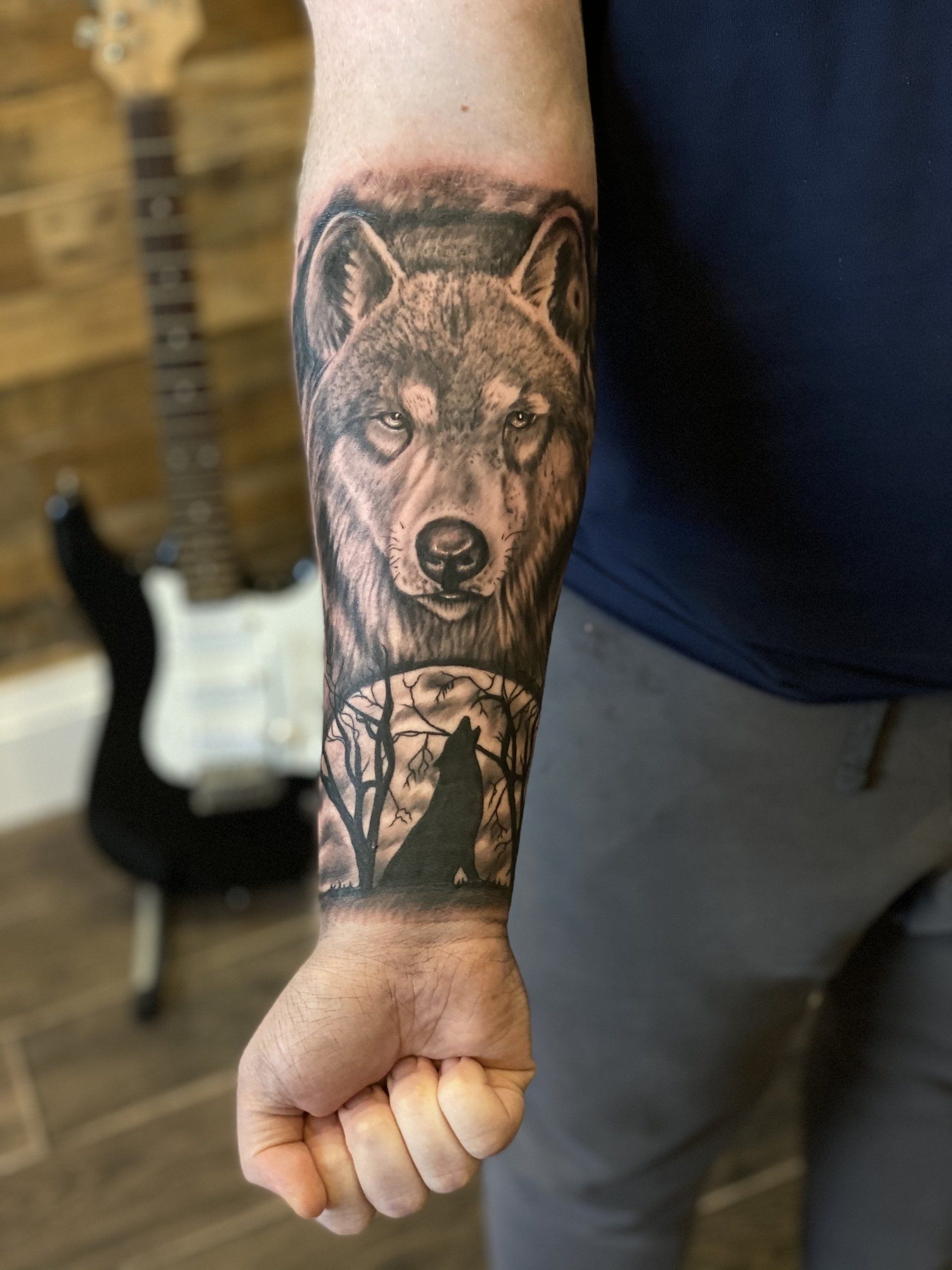 A man has a tattoo of a wolf on his forearm.