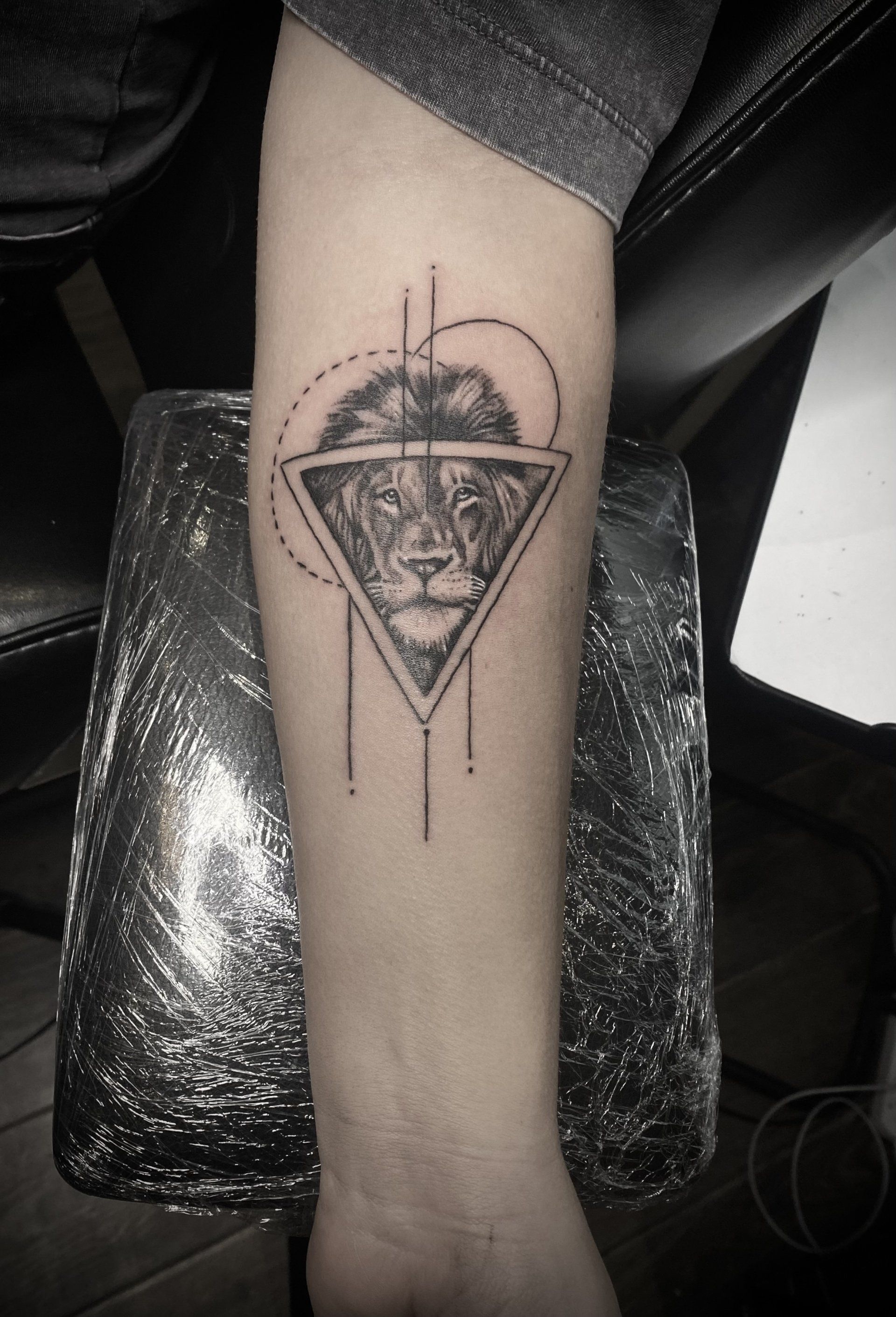 A black and white tattoo of a lion in a triangle