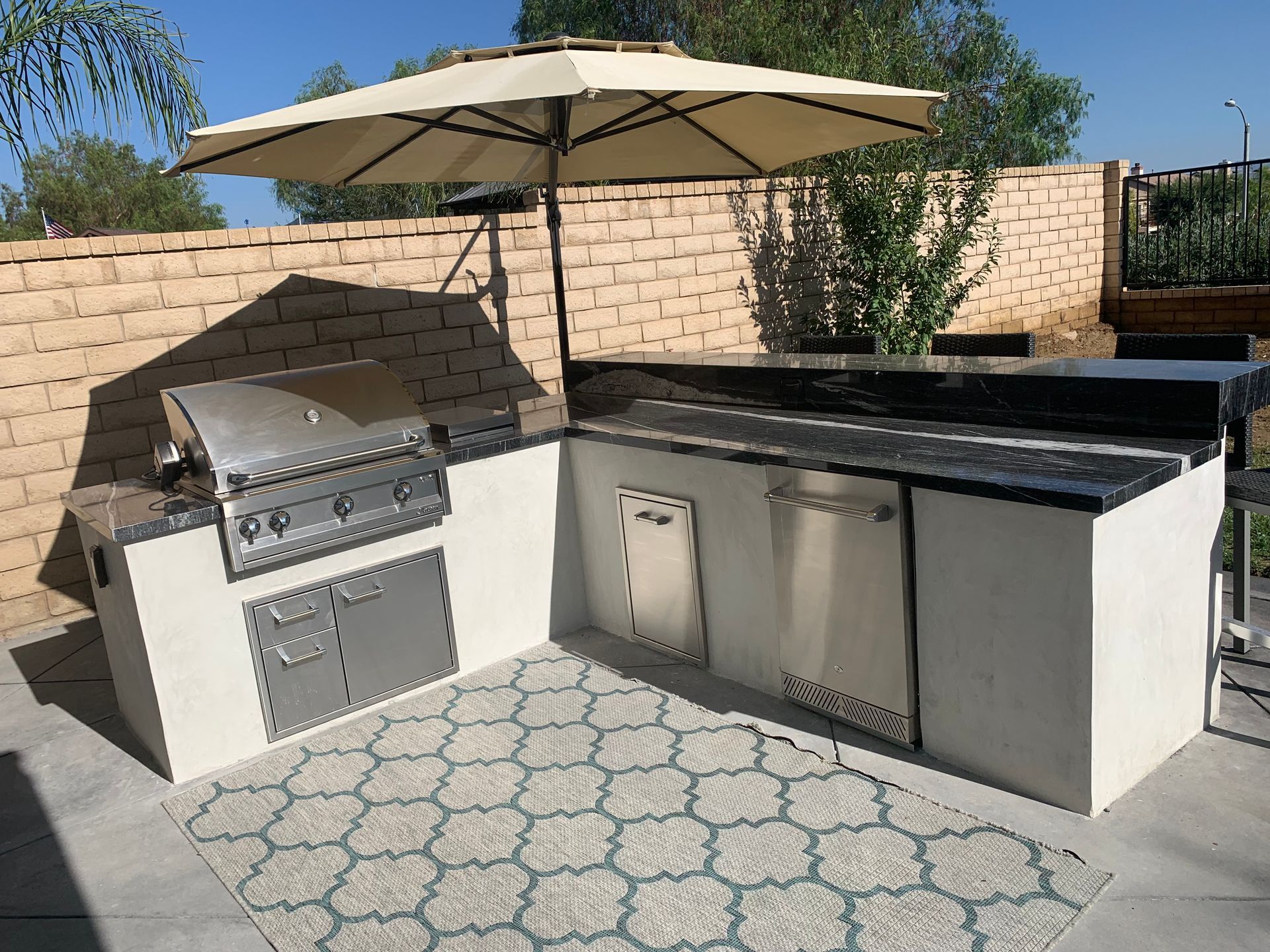 A large outdoor kitchen with a grill and umbrella.