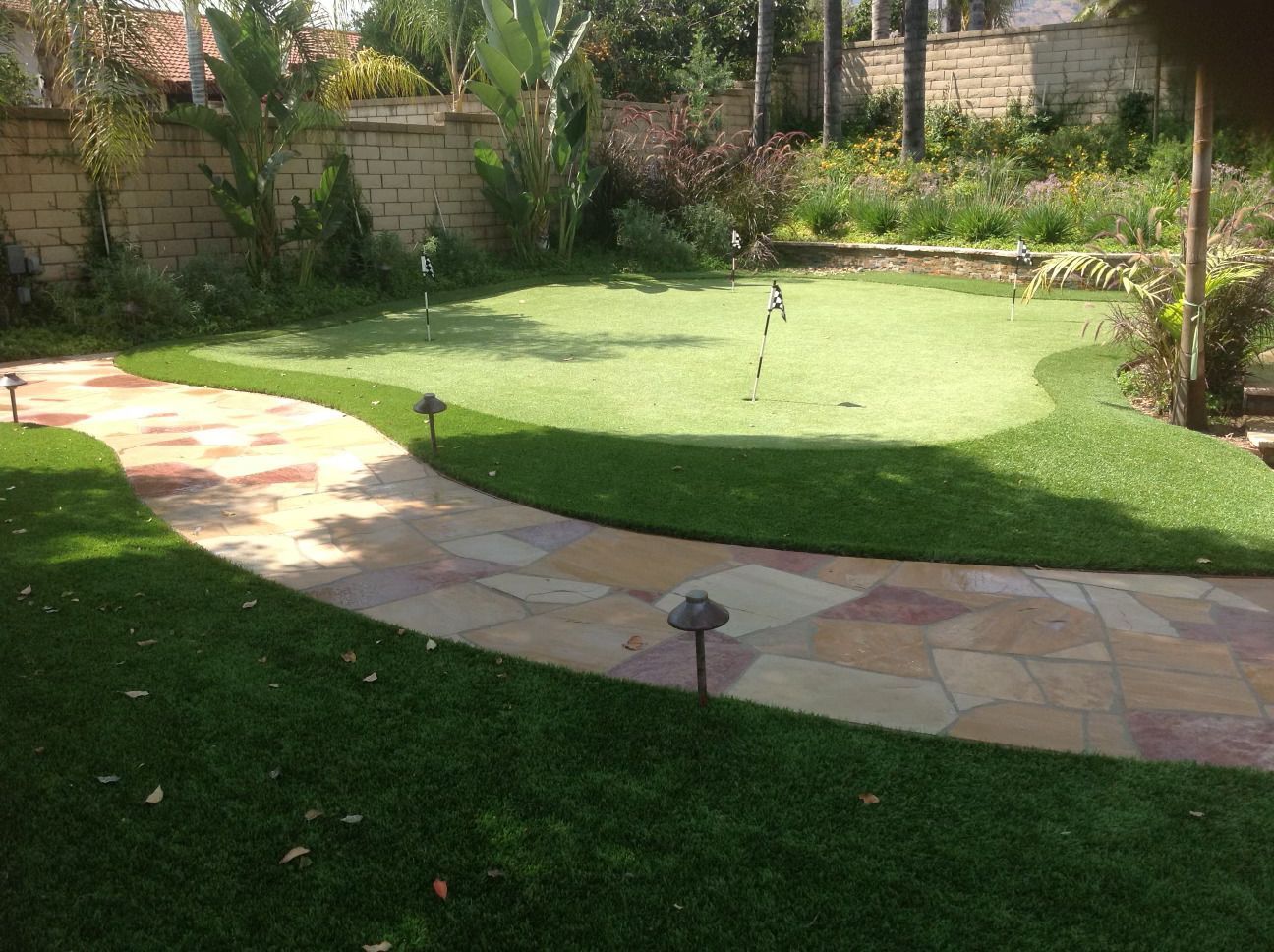A path leading to a putting green in a backyard