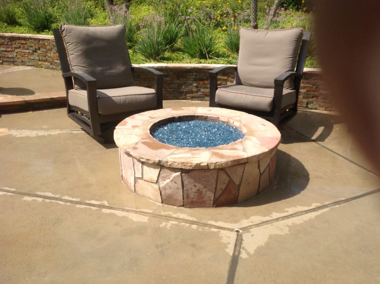 Two chairs are sitting around a fire pit on a patio.