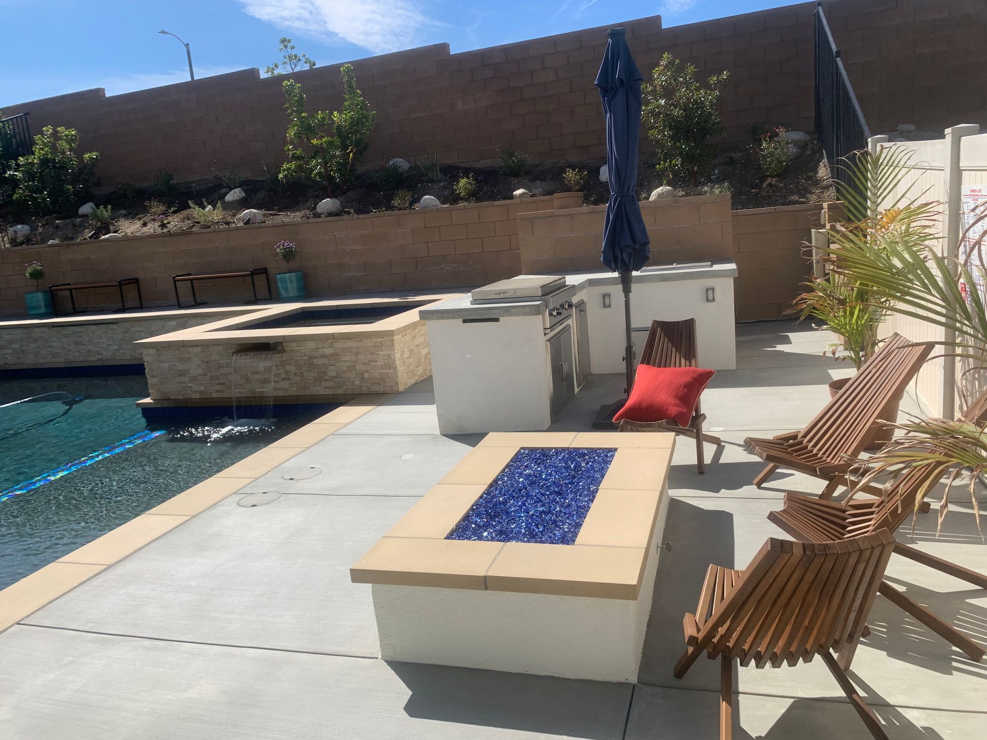 A patio with a fire pit and chairs next to a pool
