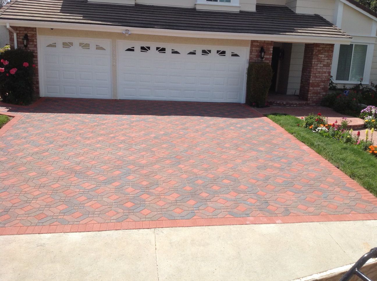 A brick driveway in front of a house with a white garage door