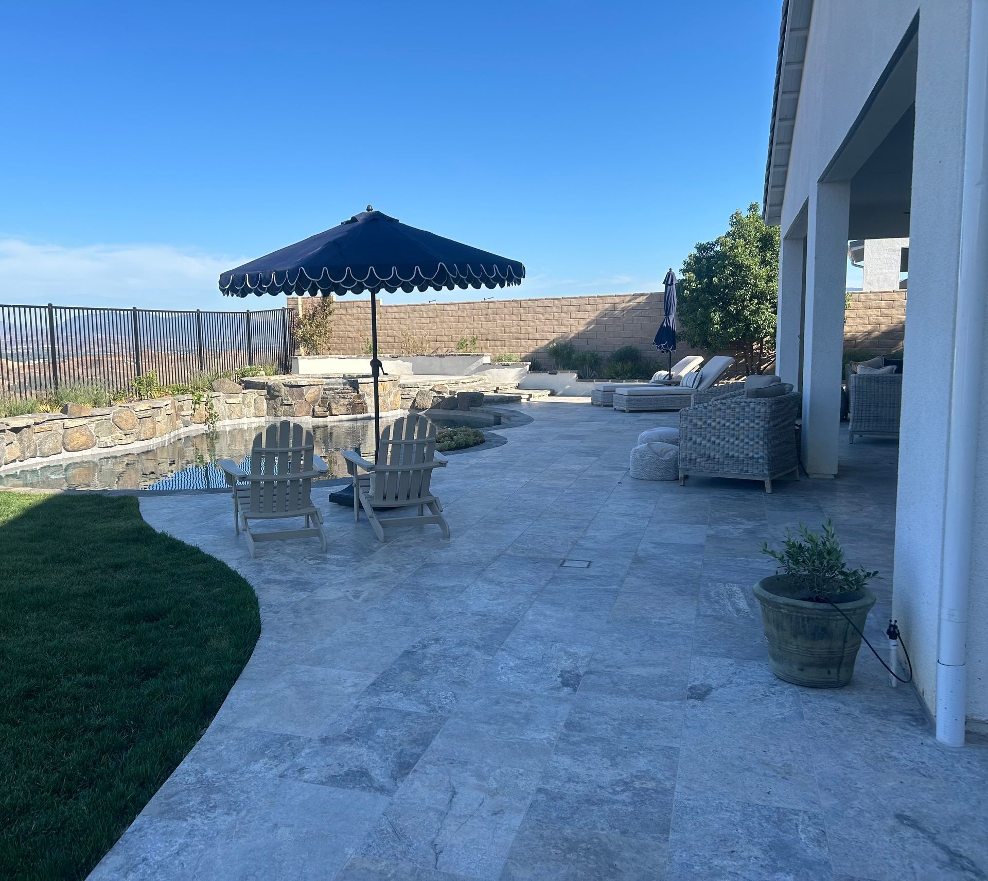 A patio with chairs umbrellas and a potted plant