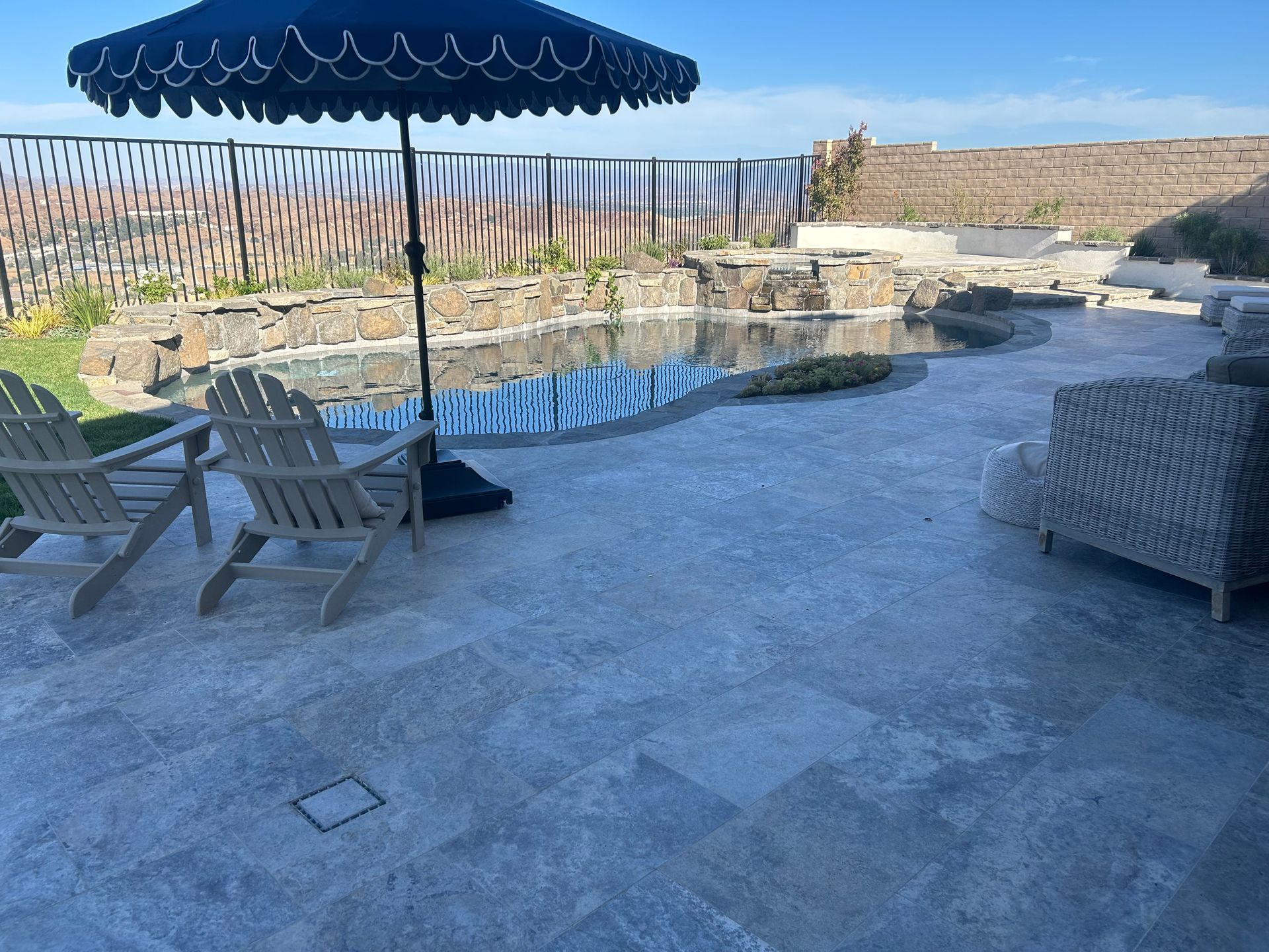 A patio with chairs and an umbrella next to a pool