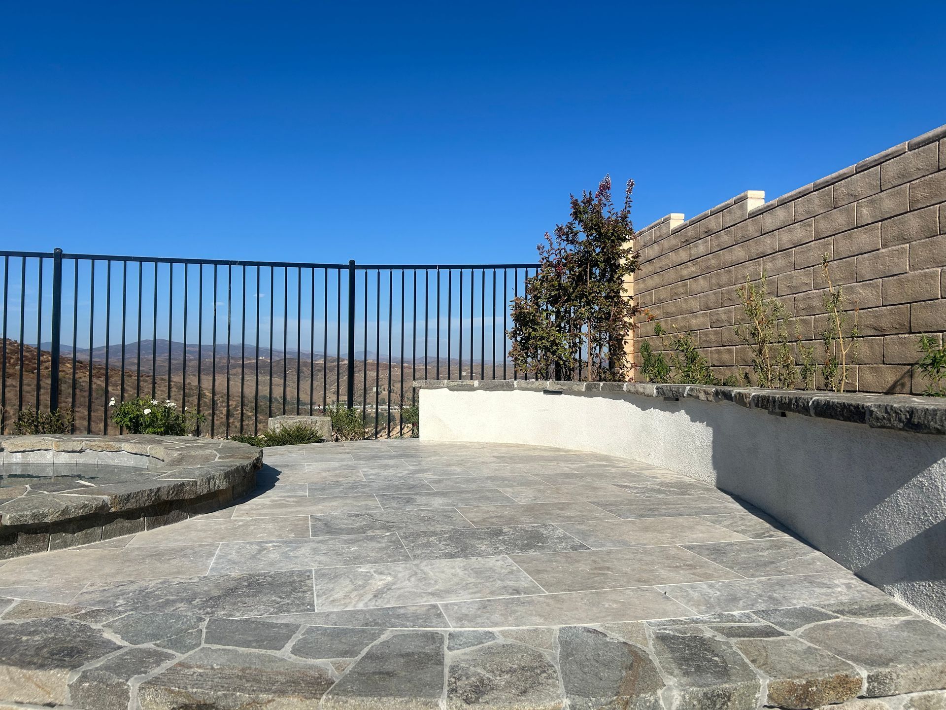 A fence surrounds a patio with a view of the mountains