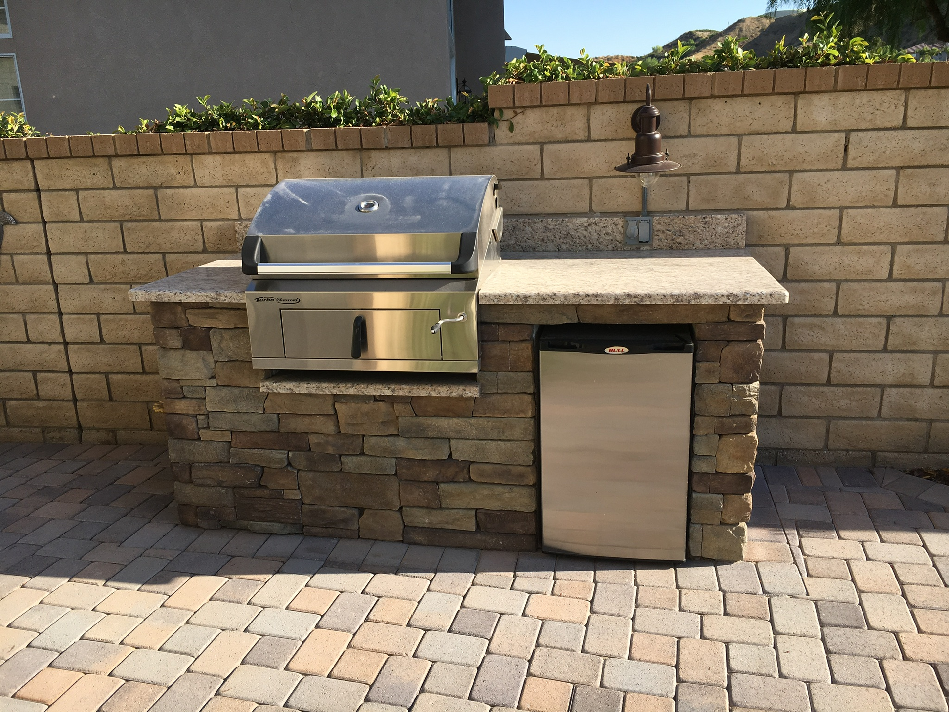 A brick wall with a grill and a trash can