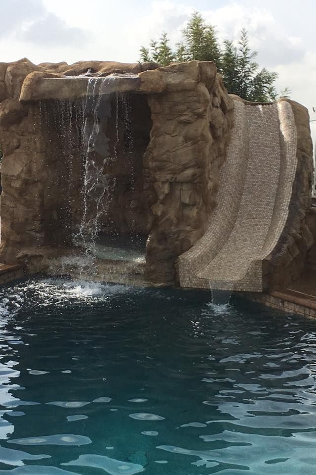 A waterfall is in the middle of a swimming pool.