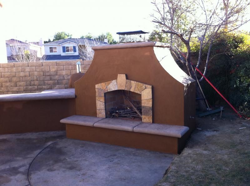 A fireplace in a backyard with a brick wall behind it