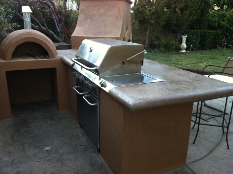 An outdoor kitchen with a grill and a pizza oven
