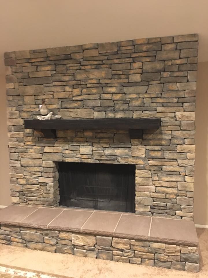 A stone fireplace with a mantle in a living room