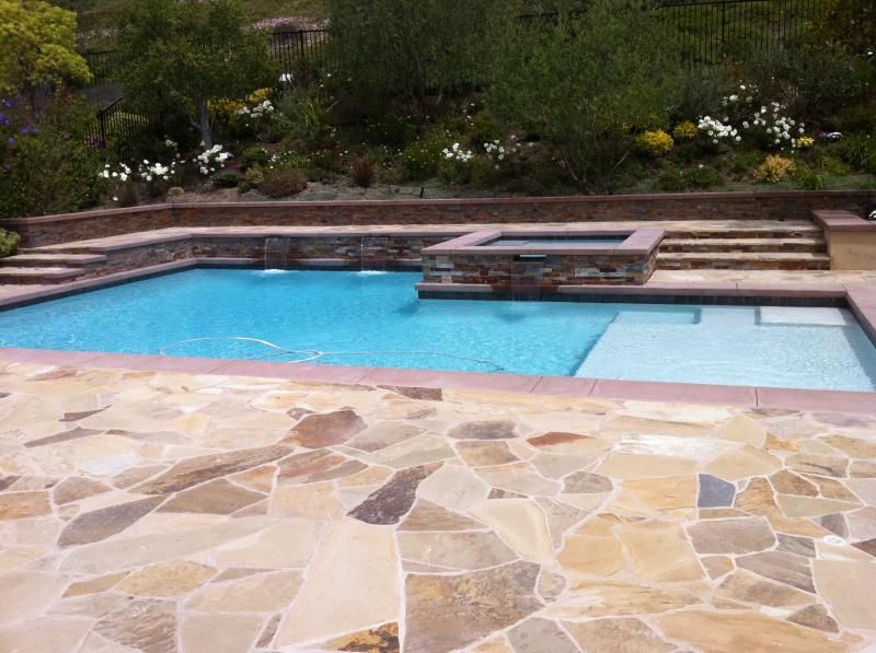 A large swimming pool is surrounded by a stone patio.