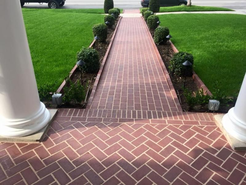 A brick walkway leading to a lush green lawn