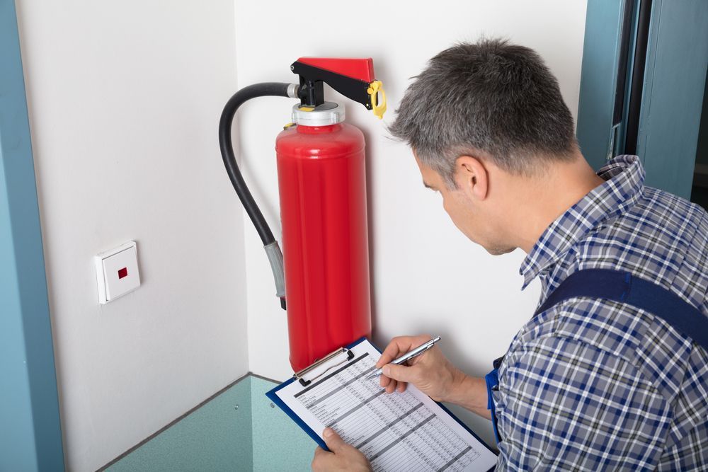 Male Professional Checking A Fire Extinguisher — Fire Safety in Coffs Harbour, NSW