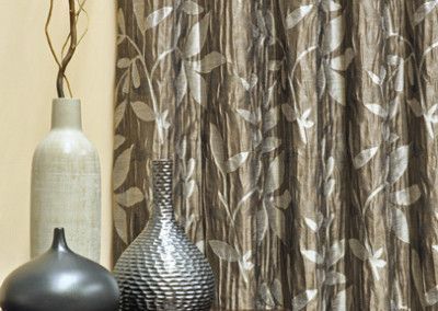Brown and white patterned curtain with vases in front.