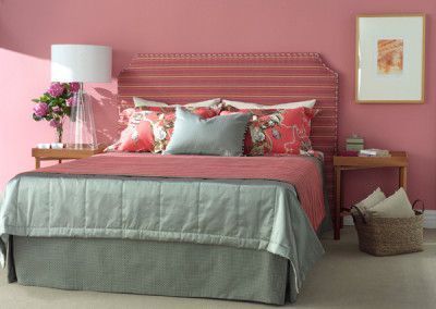 Pink bedroom with bed, nightstands, and artwork. Bed has blue and pink bedding.