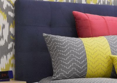 Navy blue upholstered headboard with red and patterned pillows; bedroom.