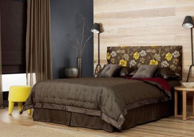 Bedroom with brown bedding, floral headboard, and a yellow stool.