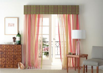 Pink and yellow striped curtains hang in front of French doors with a green valance; a room setting.