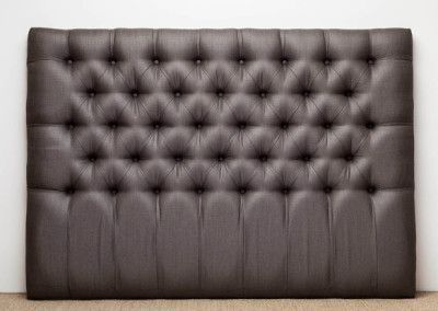 Brown button-tufted headboard against a plain white wall.