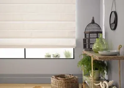 Window seat with closed gray blinds, wooden storage, and a dark wood floor.