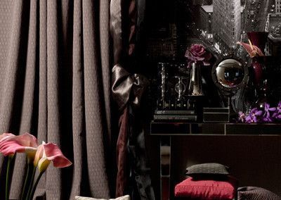 Dark room with curtains, a mirrored shelf, and flowers.