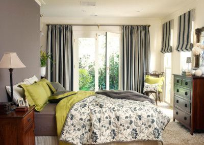 Bedroom with bed, gray walls, curtains, and a doorway to a garden. Accents of green and brown.