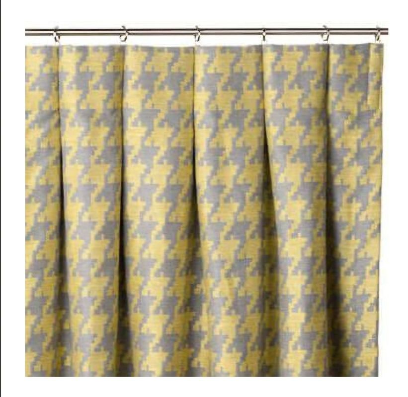 Yellow and gray houndstooth patterned curtain hanging from a silver rod.