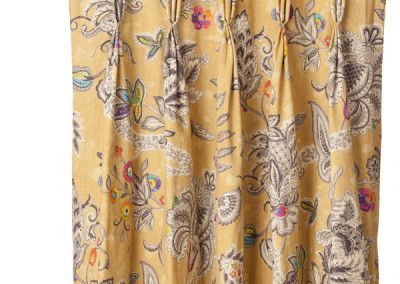 Yellow floral patterned curtain with pleats.
