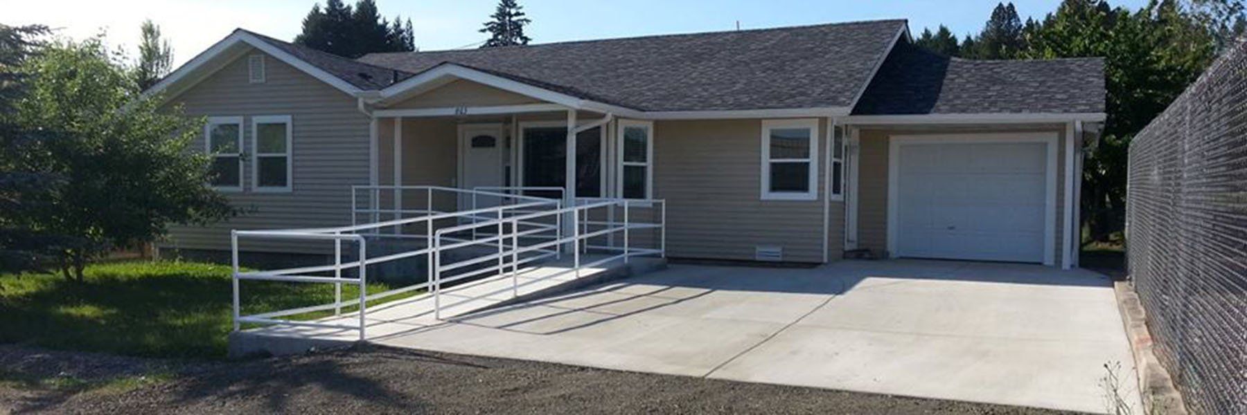 A house with a lush green lawn and bushes in front of it