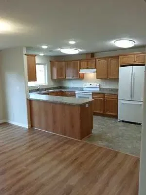 A large gray and white house with a lush green lawn in front of it.