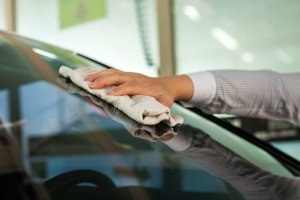 A Person is Cleaning a Car Windshield With a Towel — Shepparton Radiators & Windscreens in Cobram, VIC