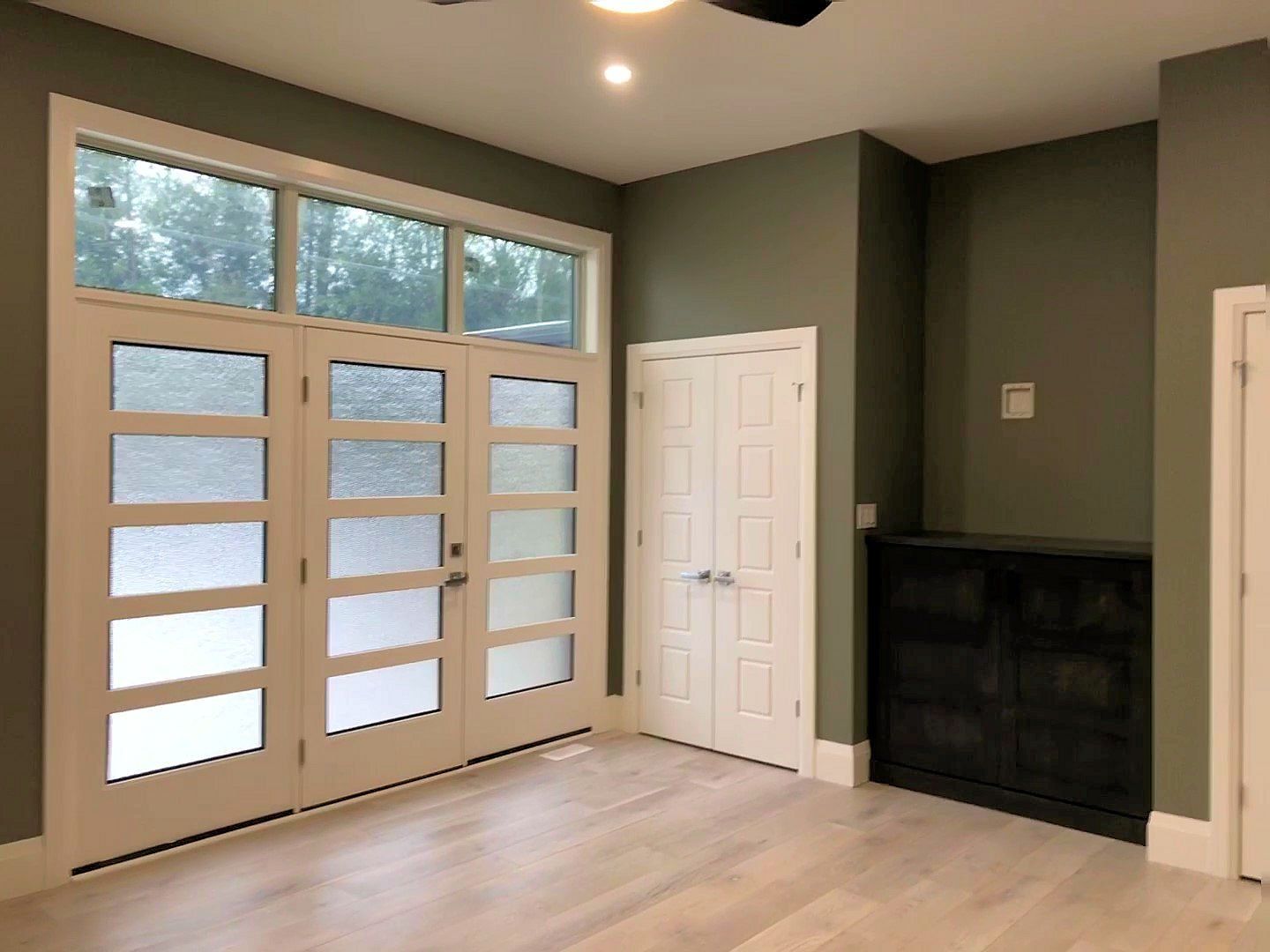 A room with a lot of windows and doors and a ceiling fan.