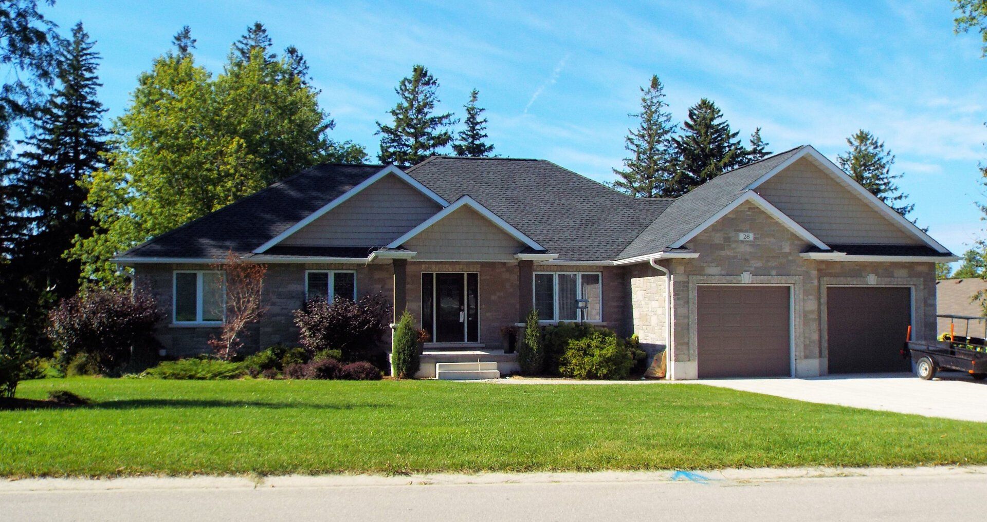 A large house with two garages and a lush green lawn